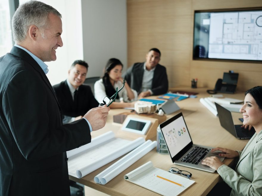 Architect Showing Miniature Building At Business Meeting With Client